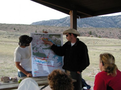 Student in cowboy hat points at topographical map