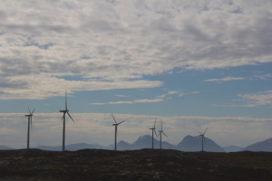 Smøla wind turbines with a mountainous background from the mainland.