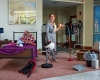 Actress Dani Solomon '13 in a jumpsuit pointing a floor lamp at herself on set